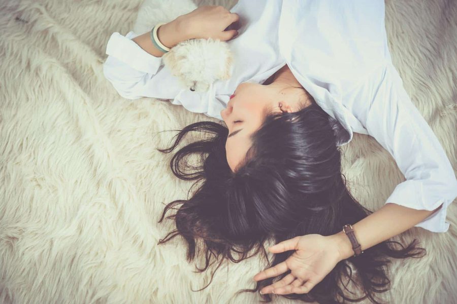 A woman peacefully sleeping with her pet dog on a soft, furry rug indoors.