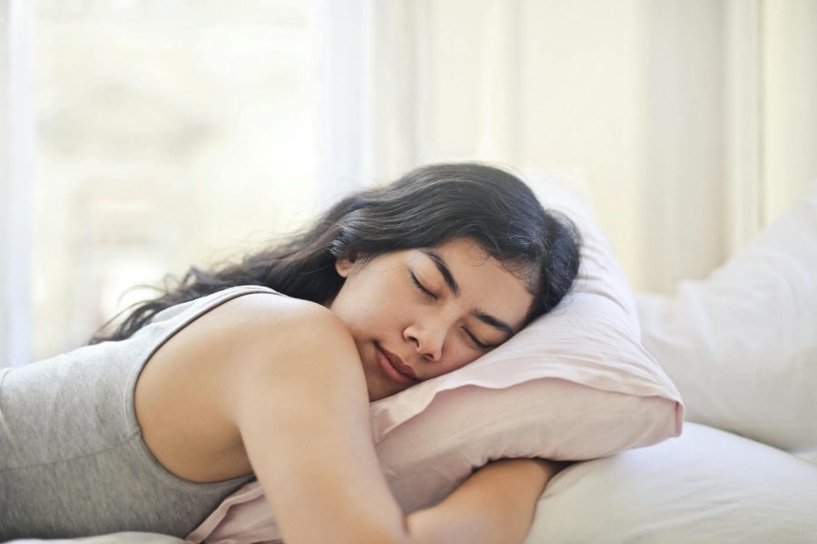 Serene woman resting on a comfortable bed with soft pillows and natural light.
